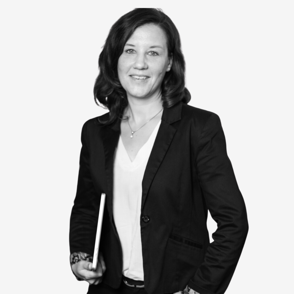 Stehende Frau mit Laptop unter dem Arm.